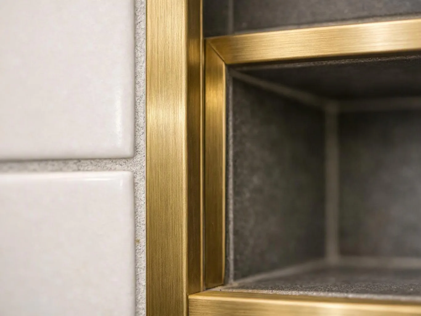 Close-up of a brass-framed recessed niche beside white tiled wall panels